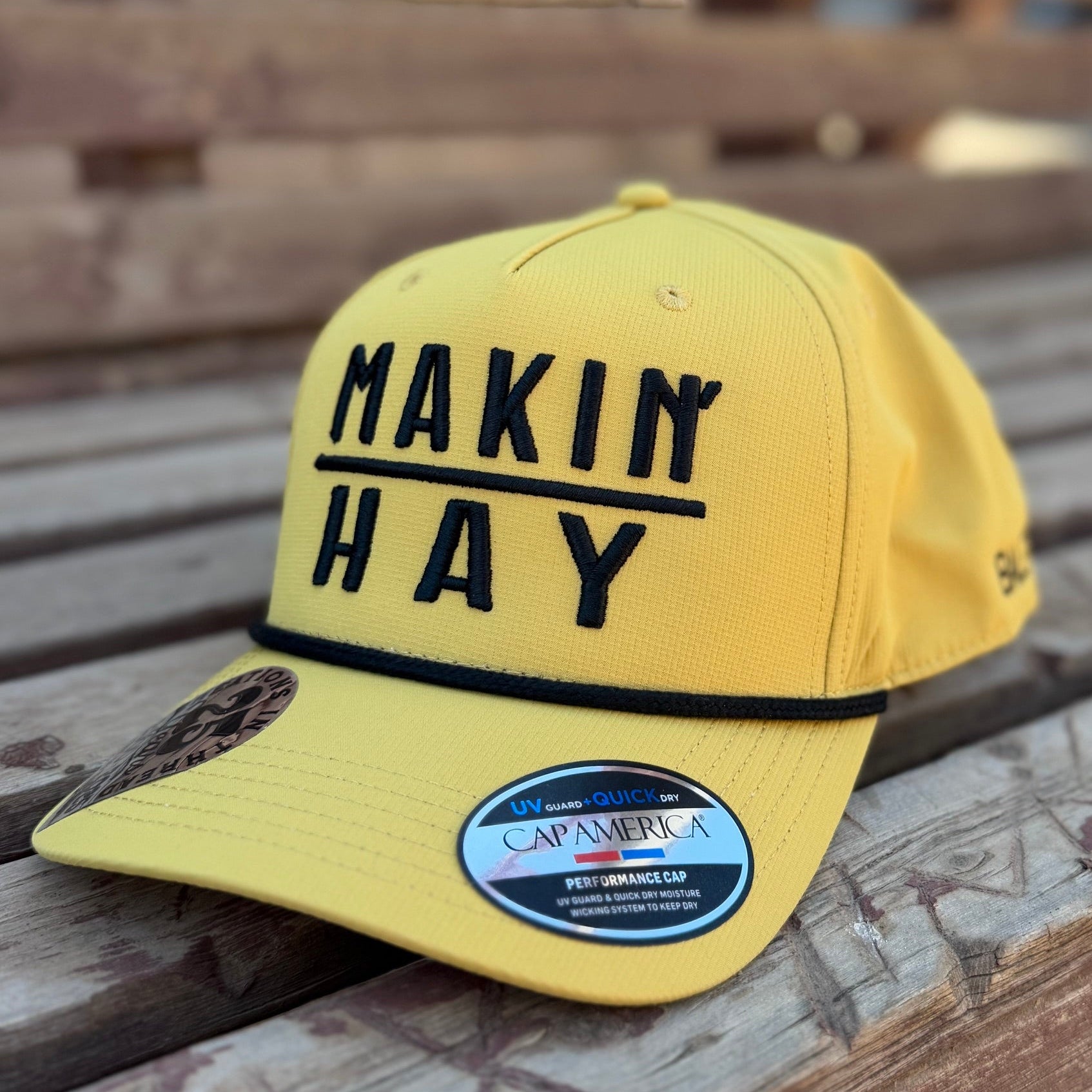 Yellow cap with 'MAKIN HAY' text on a wooden surface
