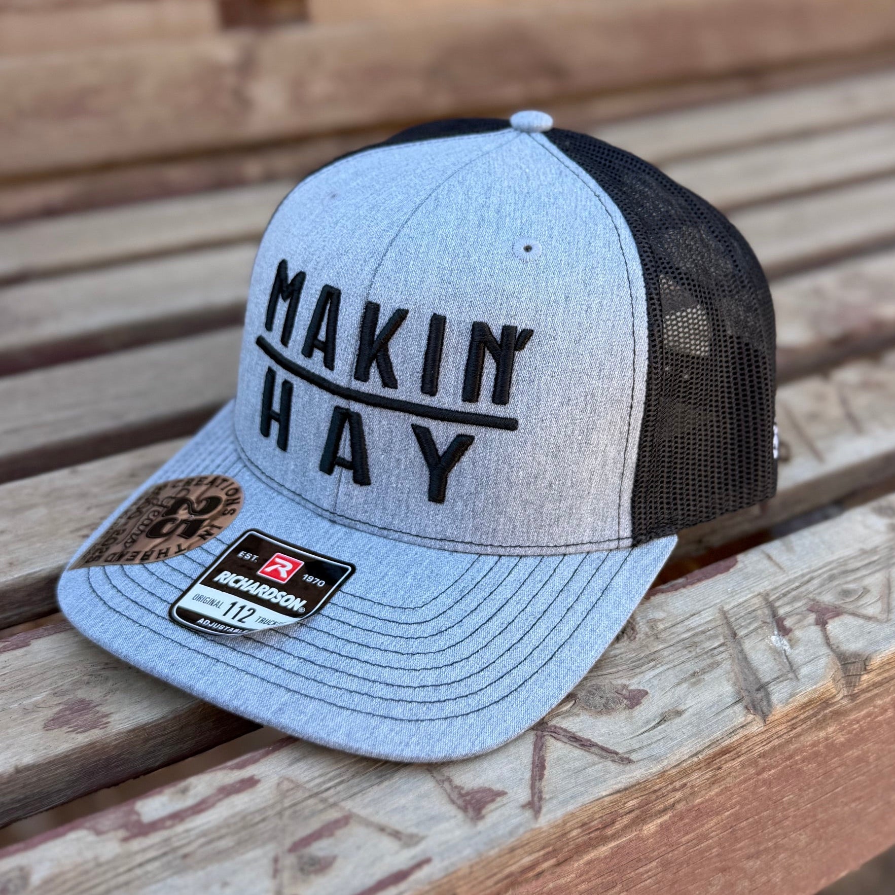 Trucker hat with 'MAKIN HAY' text on a wooden surface
