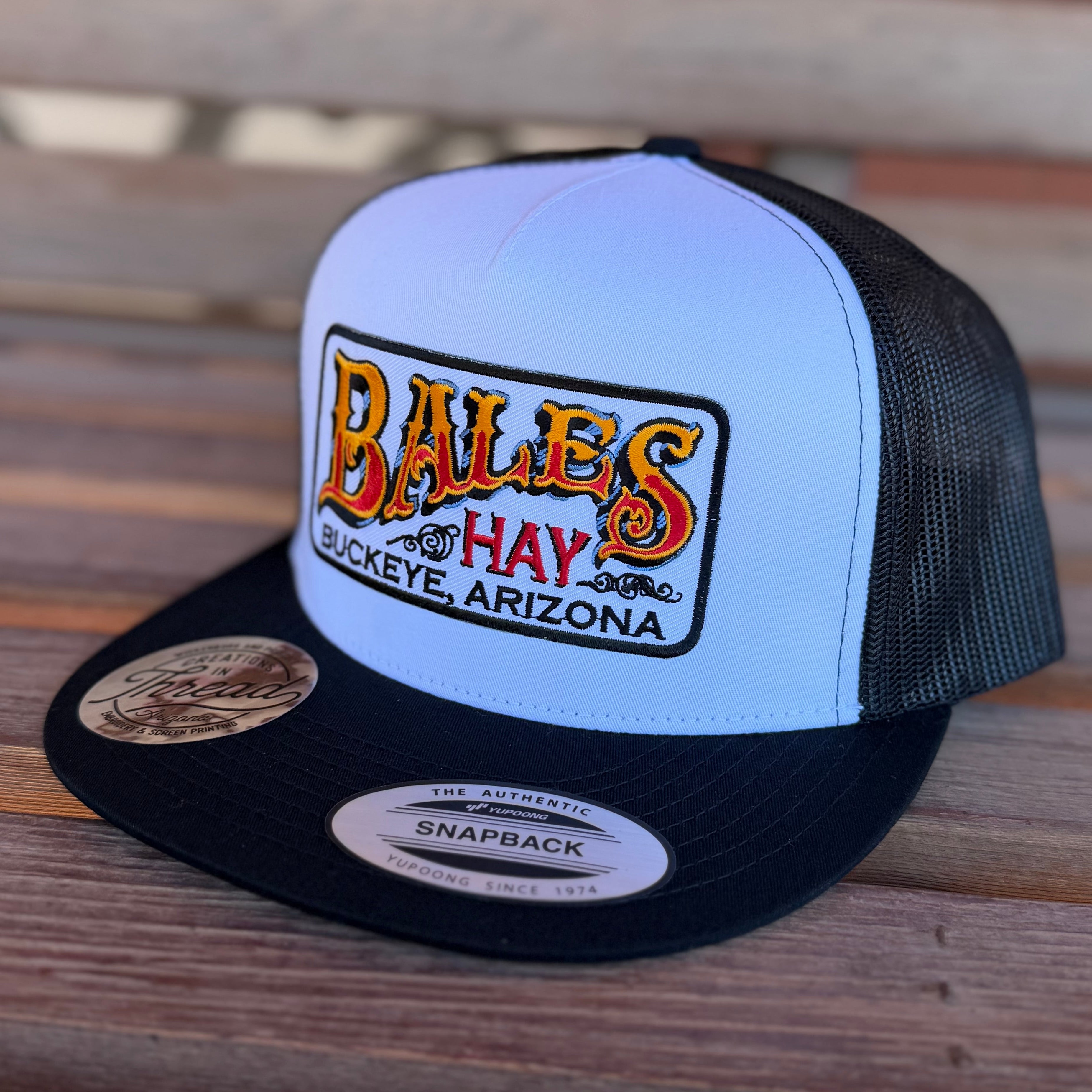 Trucker hat with 'Bales of Hay' logo on a wooden surface